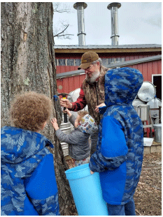 Three children watch as Dave Yeany taps a maple tree.